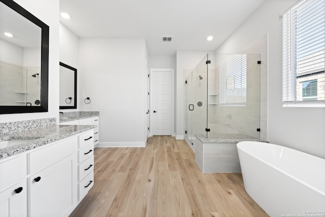 243 Wisteria Vw, Castroville, TX 78009 - full bath with vanity, a stall shower, wood finished floors, a freestanding tub, and recessed lighting