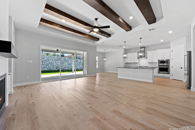 243 Wisteria Vw, Castroville, TX 78009 - unfurnished living room featuring a glass covered fireplace, light wood finished floors, a ceiling fan, baseboards, and recessed lighting