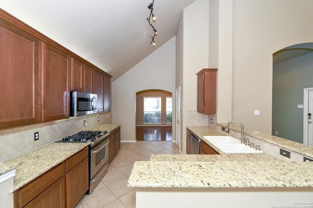 27218 Spiral Cyn, San Antonio, TX 78261 - kitchen featuring appliances with stainless steel finishes, a sink, arched walkways, tasteful backsplash, and high vaulted ceiling