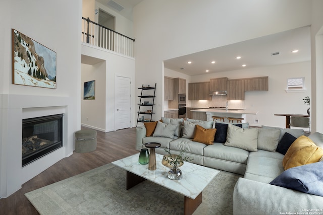 103 Valencia, Boerne, TX 78006 - living room featuring dark wood finished floors, recessed lighting, baseboards, a glass covered fireplace, and a high ceiling