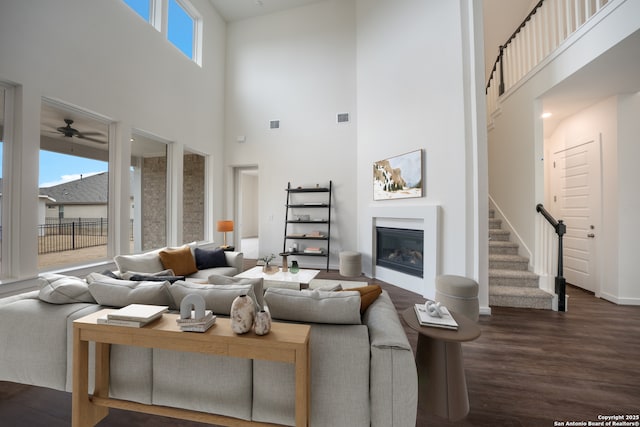 103 Valencia, Boerne, TX 78006 - living room featuring a high ceiling, dark wood finished floors, a glass covered fireplace, stairway, and baseboards
