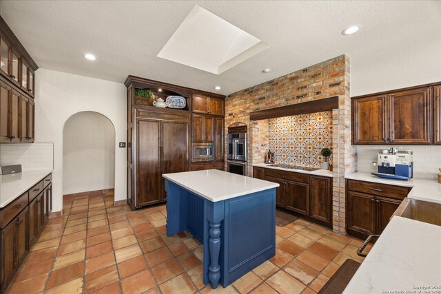 8122 Triple Crown, Fair Oaks Ranch, TX 78015 - kitchen with appliances with stainless steel finishes, decorative backsplash, a skylight, arched walkways, and a center island