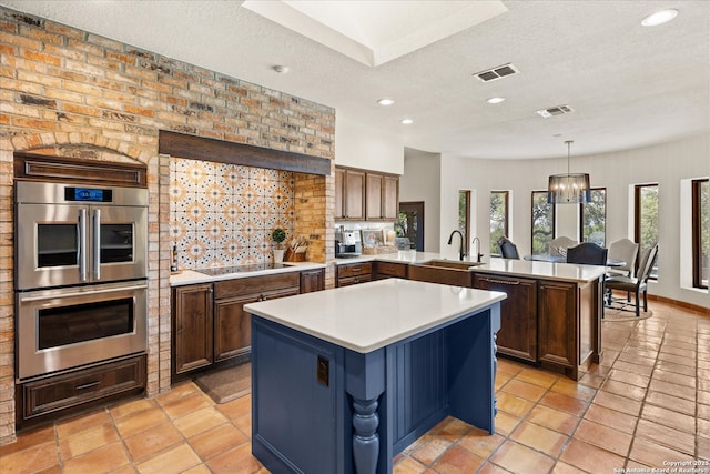 8122 Triple Crown, Fair Oaks Ranch, TX 78015 - kitchen with stainless steel double oven, a peninsula, black electric stovetop, light countertops, and a textured ceiling