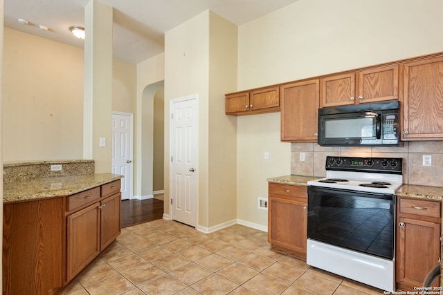 24931 Crescent Run, San Antonio, TX 78258 - kitchen with electric range, black microwave, arched walkways, brown cabinets, and backsplash