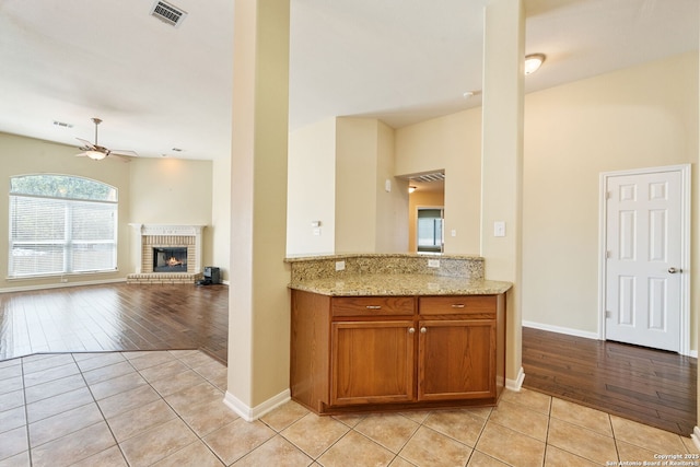 24931 Crescent Run, San Antonio, TX 78258 - kitchen featuring ceiling fan, light tile patterned floors, brown cabinets, and light stone countertops