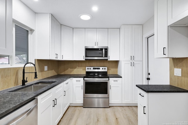 246 Bamburgh Dr, San Antonio, TX 78216 - kitchen with stainless steel appliances, a sink, white cabinets, light wood-style flooring, and decorative backsplash