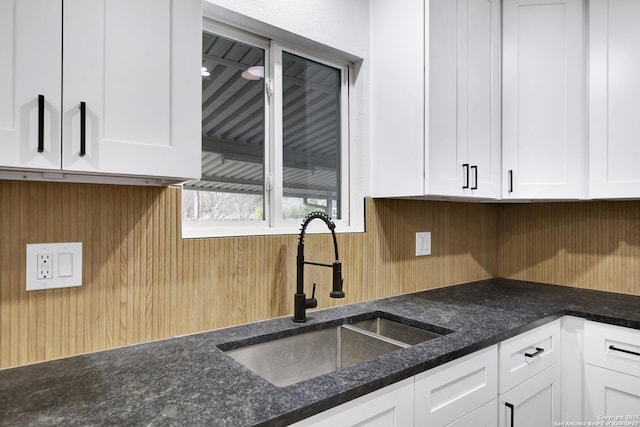 246 Bamburgh Dr, San Antonio, TX 78216 - kitchen with a sink, white cabinetry, wood walls, and dark stone counters