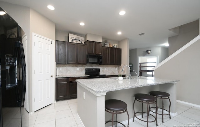 5727 Ivans Farm, San Antonio, TX 78244 - kitchen featuring black appliances, a sink, a breakfast bar, dark brown cabinets, and backsplash