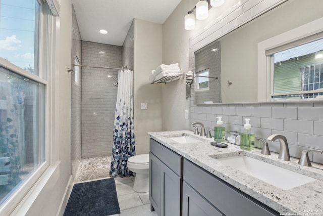 621 Center St, San Antonio, TX 78202 - full bathroom featuring tiled shower, toilet, double vanity, tile patterned floors, and tasteful backsplash