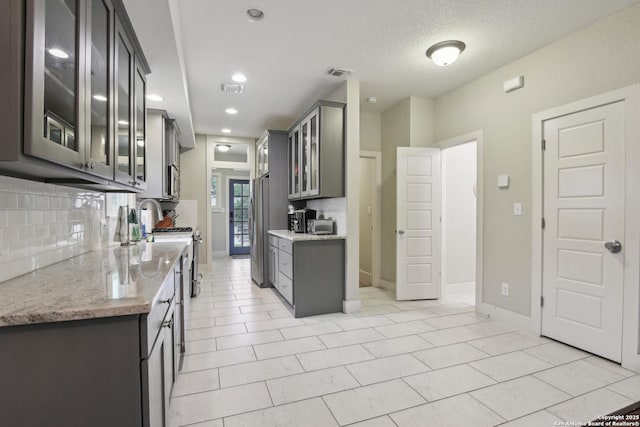 621 Center St, San Antonio, TX 78202 - kitchen with gray cabinets, backsplash, glass insert cabinets, stainless steel appliances, and recessed lighting