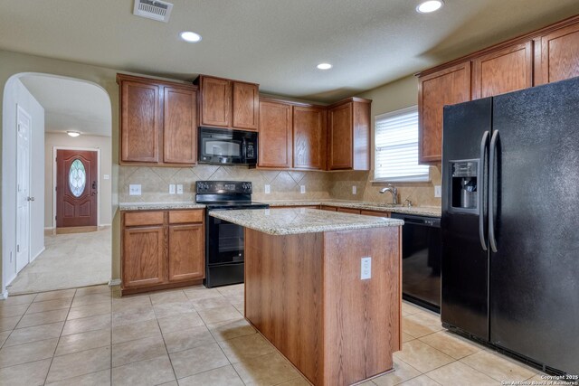 114 Arcadia Pl, Cibolo, TX 78108 - kitchen with black appliances, arched walkways, a center island, light tile patterned flooring, and recessed lighting