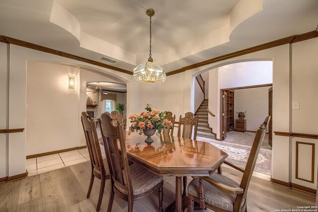 13742 Corinth, Universal City, TX 78148 - dining space with arched walkways, light wood-type flooring, a chandelier, stairway, and a tray ceiling