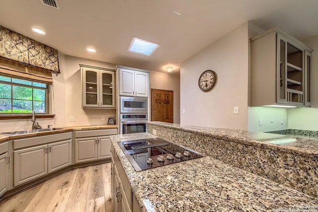 13742 Corinth, Universal City, TX 78148 - kitchen with appliances with stainless steel finishes, a sink, light wood-style flooring, glass insert cabinets, and a skylight