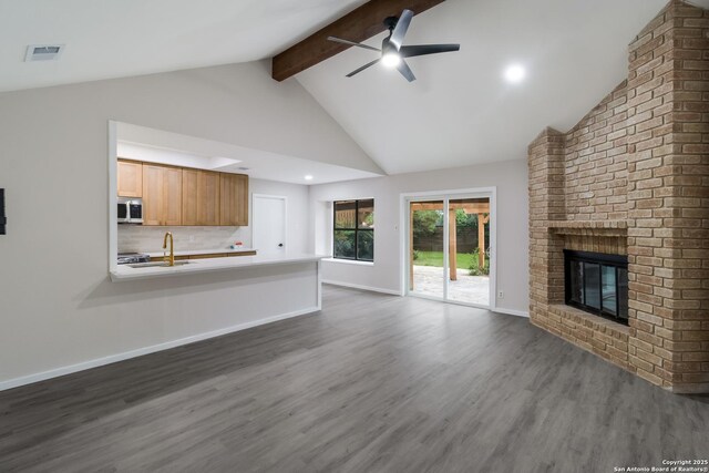 7927 Misty Park, San Antonio, TX 78250 - unfurnished living room featuring a ceiling fan, beam ceiling, dark wood-style flooring, a fireplace, and baseboards