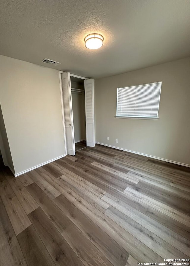 459 Maddux, San Antonio, TX 78227 - unfurnished bedroom featuring a textured ceiling, a closet, dark wood-type flooring, and baseboards