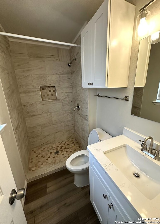 459 Maddux, San Antonio, TX 78227 - bathroom featuring wood finished floors, a tile shower, toilet, and vanity