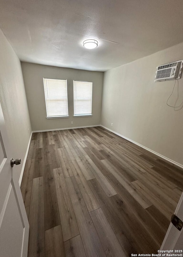 459 Maddux, San Antonio, TX 78227 - spare room with a wall mounted AC, dark wood-style floors, and baseboards