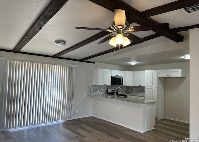 459 Maddux, San Antonio, TX 78227 - kitchen with stainless steel microwave, beamed ceiling, a peninsula, dark wood-style floors, and white cabinets
