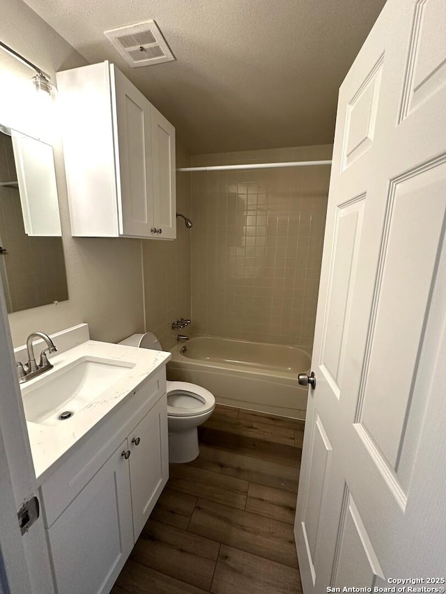 459 Maddux, San Antonio, TX 78227 - bathroom with toilet, vanity, wood finished floors, a textured ceiling, and shower / tub combination