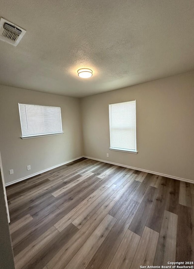 459 Maddux, San Antonio, TX 78227 - unfurnished room featuring plenty of natural light, dark wood-type flooring, a textured ceiling, and baseboards