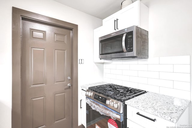 4207 Tallulah, San Antonio, TX 78218 - kitchen featuring appliances with stainless steel finishes, light stone counters, decorative backsplash, white cabinetry, and wood finished floors