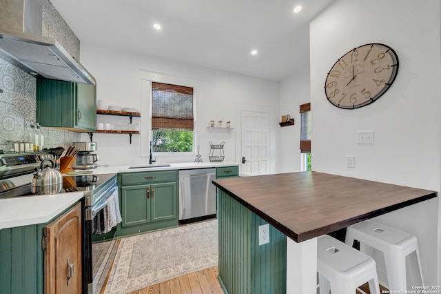 419 Wickes, San Antonio, TX 78210 - kitchen with appliances with stainless steel finishes, green cabinetry, wall chimney range hood, open shelves, and light wood-style flooring