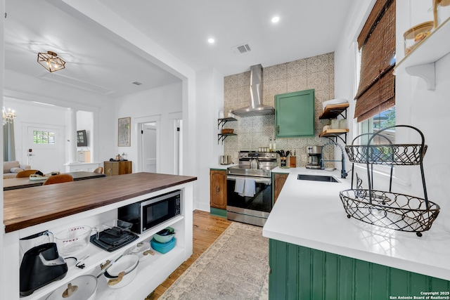 419 Wickes, San Antonio, TX 78210 - kitchen featuring stainless steel appliances, wall chimney exhaust hood, a sink, open shelves, and butcher block counters