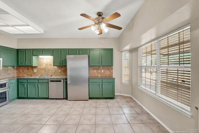 1314 Acorn, Hondo, TX 78861 - kitchen with green cabinets, stainless steel appliances, decorative backsplash, a ceiling fan, and a sink