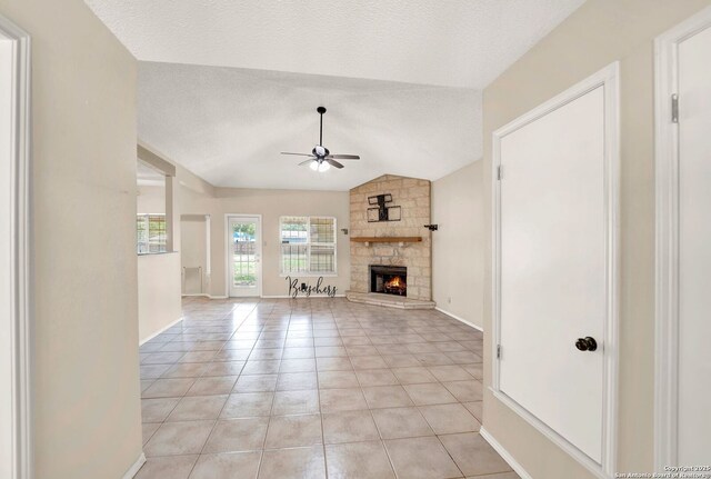 1314 Acorn, Hondo, TX 78861 - unfurnished living room featuring ceiling fan, a fireplace, vaulted ceiling, a textured ceiling, and light tile patterned flooring