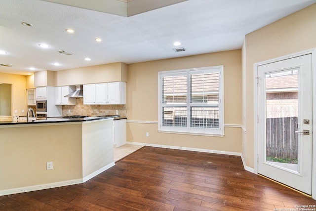 2426 Enfield Grove, San Antonio, TX 78231 - kitchen featuring wall chimney range hood, dark countertops, dark wood-style flooring, white cabinets, and recessed lighting