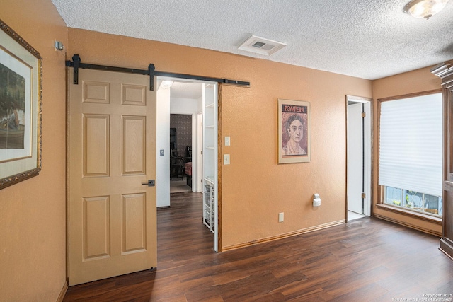 5954 Oak Run, San Antonio, TX 78247 - empty room with a barn door, a textured ceiling, dark wood finished floors, baseboards, and a textured wall