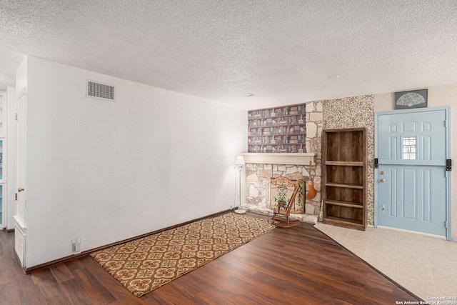 5954 Oak Run, San Antonio, TX 78247 - unfurnished living room with wood finished floors, a textured ceiling, a stone fireplace, and baseboards