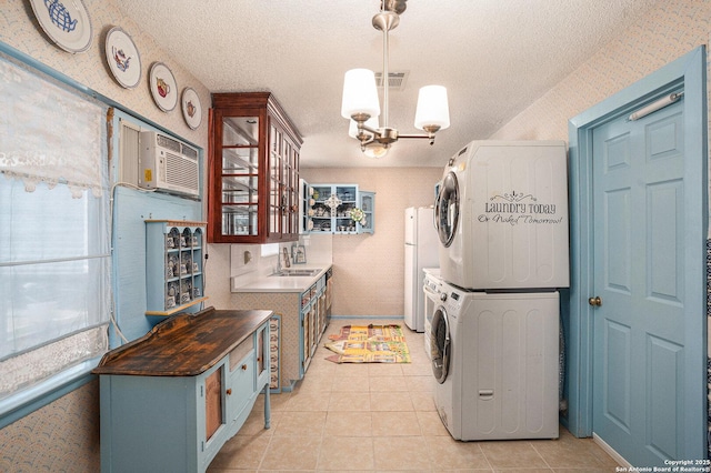 5954 Oak Run, San Antonio, TX 78247 - laundry area featuring stacked washer / drying machine, a wall unit AC, a textured ceiling, light tile patterned floors, and a chandelier