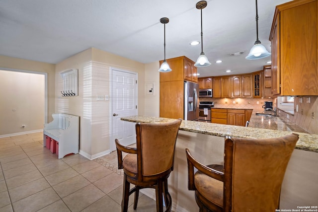 103 River Mdw, Castroville, TX 78009 - kitchen with appliances with stainless steel finishes, brown cabinets, a peninsula, baseboards, and backsplash