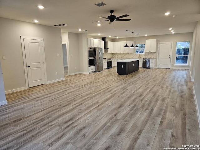 unfurnished living room with recessed lighting, light wood finished floors, ceiling fan, baseboards, and a sink