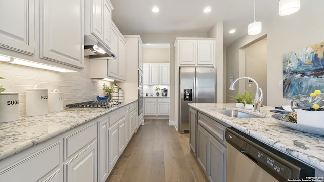 4207 Colina Crst, San Antonio, TX 78261 - kitchen featuring stainless steel appliances, a sink, under cabinet range hood, light wood-type flooring, and backsplash