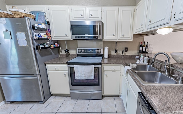5003 Rustic Rdg, San Antonio, TX 78228 - kitchen featuring appliances with stainless steel finishes, a sink, white cabinets, light tile patterned flooring, and dark countertops