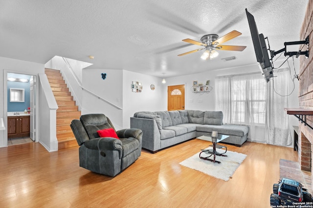 1130 Stone Gdn, New Braunfels, TX 78130 - living room with ceiling fan, wood finished floors, stairs, a textured ceiling, and a brick fireplace