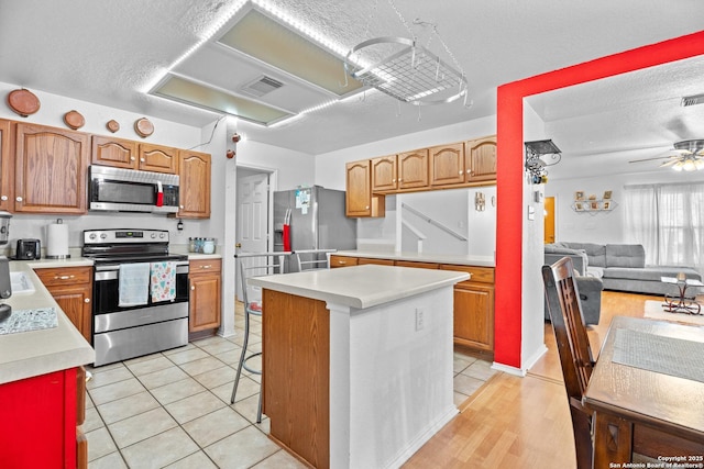 1130 Stone Gdn, New Braunfels, TX 78130 - kitchen featuring appliances with stainless steel finishes, light countertops, open floor plan, a kitchen island, and light tile patterned floors
