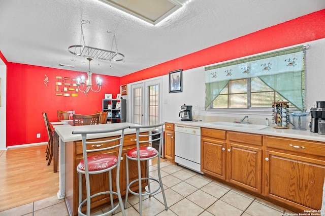 1130 Stone Gdn, New Braunfels, TX 78130 - kitchen with white dishwasher, a sink, a center island, brown cabinetry, and a textured ceiling