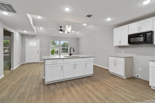 519 W Mitchell, San Antonio, TX 78204 - kitchen featuring black microwave, a sink, light wood-style flooring, white cabinetry, and baseboards