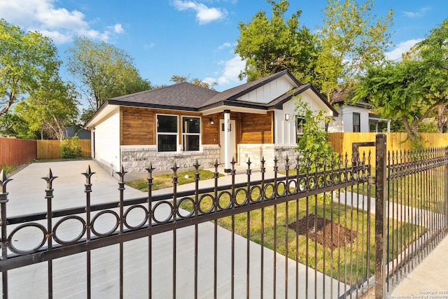 519 W Mitchell, San Antonio, TX 78204 - view of front of home with a shingled roof, stone siding, a fenced front yard, a gate, and board and batten siding
