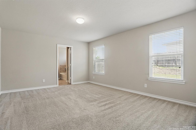 unfurnished bedroom featuring baseboards, carpet, and ensuite bathroom