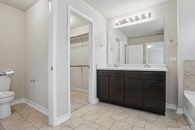 bathroom featuring toilet, tile patterned flooring, double vanity, and a spacious closet