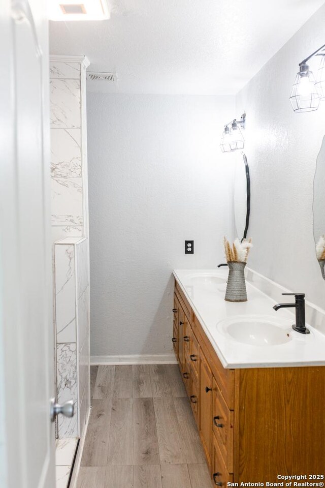 5311 Moreville Farm, San Antonio, TX 78228 - bathroom featuring wood finished floors, double vanity, and baseboards