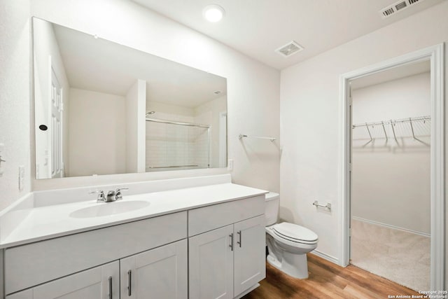 6322 Silver Pegasus, San Antonio, TX 78218 - bathroom featuring wood finished floors, toilet, a shower, a spacious closet, and vanity