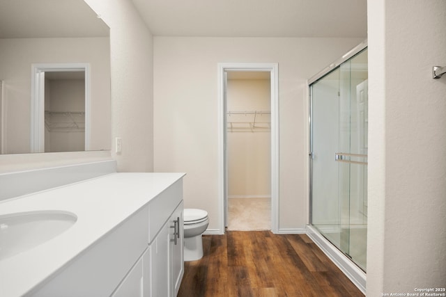 13731 Redtail Lndg, San Antonio, TX 78253 - full bathroom with a walk in closet, vanity, wood finished floors, toilet, and a stall shower