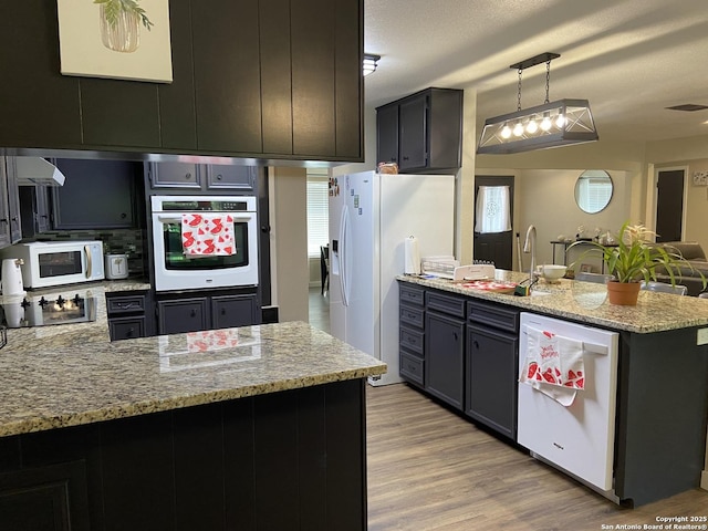 326 Riverview, Mcqueeney, TX 78123 - kitchen with white appliances, a peninsula, a sink, light wood-type flooring, and light stone counters