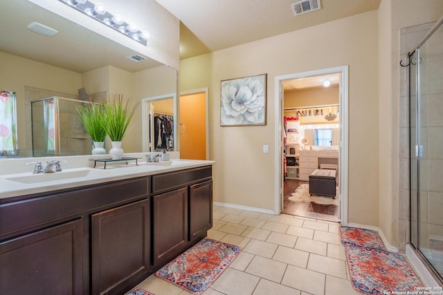 11607 Pelican Pass, San Antonio, TX 78221 - bathroom featuring a shower stall, a spacious closet, tile patterned flooring, baseboards, and double vanity