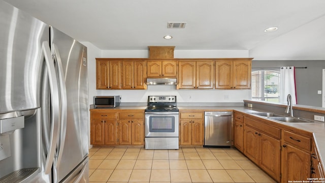 1070 Northpark, New Braunfels, TX 78130 - kitchen with stainless steel appliances, a sink, under cabinet range hood, light tile patterned floors, and brown cabinetry
